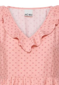 Blouse rose à petit motif floral rouge, encolure en V, col à volants et étiquette de marque ICHI à l'encolure.