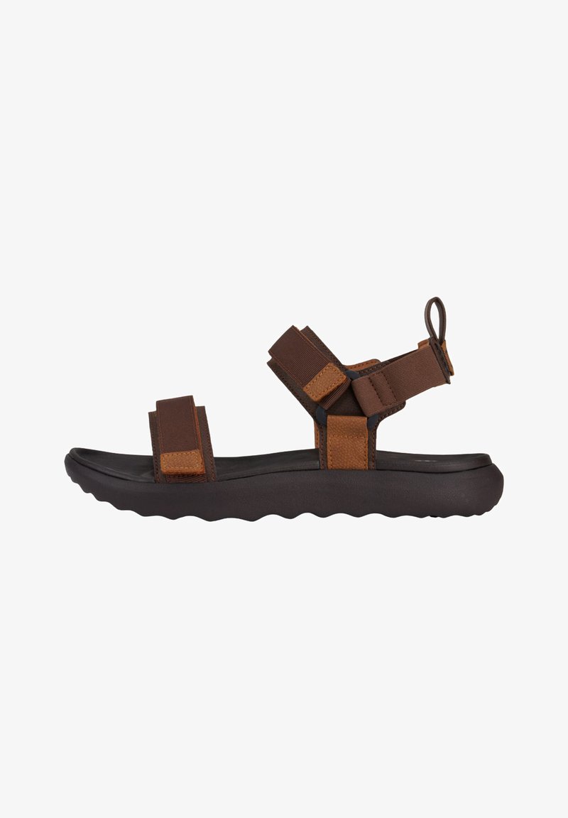 Sandale marron avec de larges sangles en tissu, une semelle noire rembourrée et une semelle extérieure texturée. Équipée de sangles ajustables pour un maintien sûr.