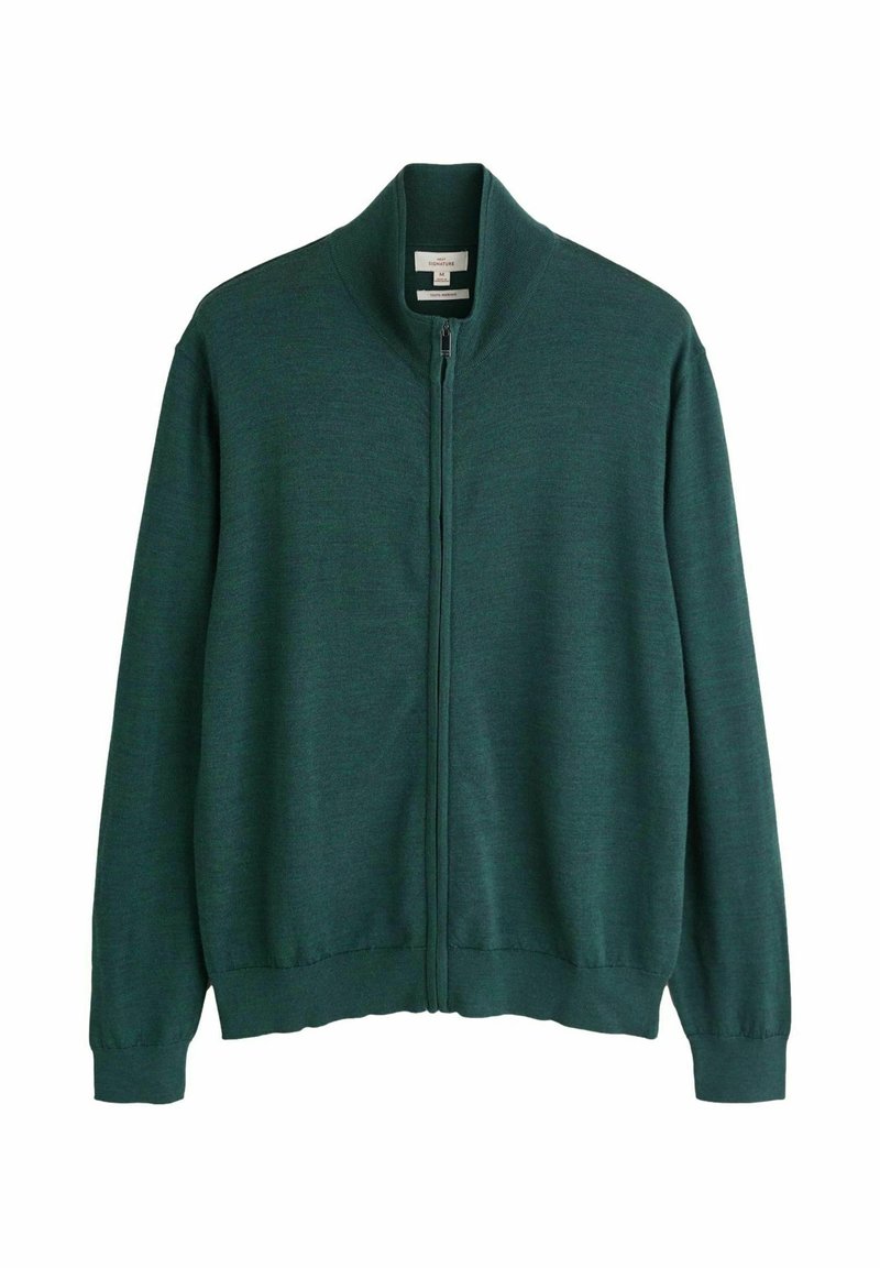 Tumši zaļš jaka ar rāvējslēdzēju un garām piedurknēm, ar ribotām aprocēm, apkakli un apakšmalu, novietota uz baltas fona.