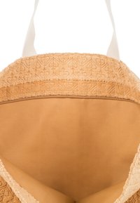 Sac en tissu beige en forme de cercle avec une couche extérieure texturée et une doublure intérieure lisse ; il présente une bordure décorative avec un motif subtil.