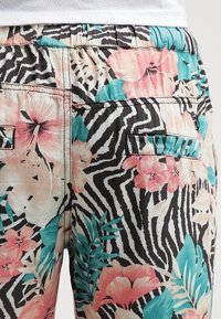 Pantalons à motifs floraux et rayés zèbre dans des couleurs pastel, avec une taille élastique et deux poches arrière. Tissu en mélange de coton.