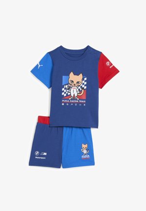 Zils un sarkans divdaļīgs komplekts, kurā ir karikatūru kaķis sacīkšu tērpā. Izgatavots no mīksta auduma ar īsām piedurknēm un šortiem, iekļaujot zīmola detaļas.