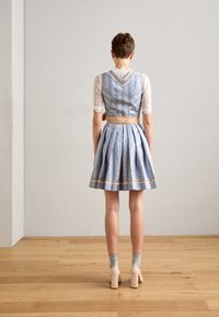 Blau-weiß gemustertes Kleid mit tailliertem Oberteil, Spitzenärmeln und ausgestellt Rock. Mit einem goldenen Streifen am Saum akzentuiert.