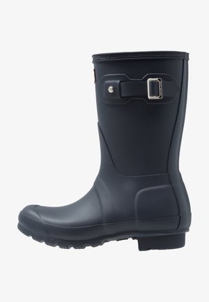 Musthave musta kummisaapad ümarate varvastega, tekstureeritud tallaga ja reguleeritava rihma detailiga. Sile pind mati viimistlusega.