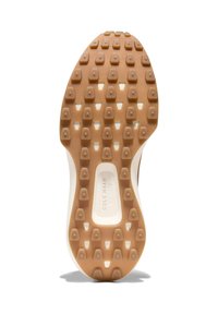 Sneakersula i gummi, i en tan färg med flera hexagonala mönster för bra grepp och en vit mellansula. Logotyp synlig i mitten.