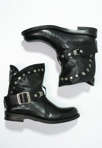 Czarne skórzane botki za kostkę z podwiniętym mankietem, ozdobione ćwiekami oraz paskiem z metalową klamrą po boku, na niskim drewnianym obcasie.