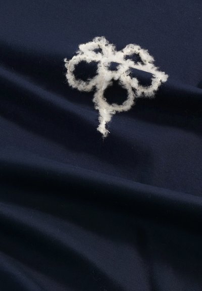 Navy fabric featuring a white fuzzy embroidered floral design, with overlapping circular shapes and a textured finish.
