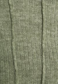 Dzianina w kolorze oliwkowym, z pionowym prążkowaniem, miękką fakturą i lekko puszystym wyglądem. Idealna do odzieży lub akcesoriów.