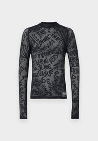 Čierny top s dlhým rukávom z priehľadnej sieťoviny so štruktúrovaným vzorom s rôznymi typografiami. Okrúhly výstrih a priliehavý strih, s brandovanou nášivkou na leme.