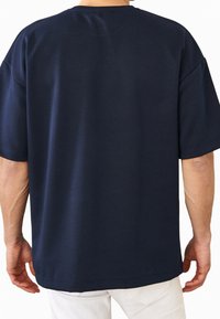 Camiseta de manga corta azul marino, hecha de una mezcla de algodón, con un corte relajado y un dobladillo recto sin patrones ni acentos visibles.