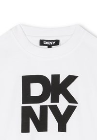 Biała bawełniana koszulka z okrągłym dekoltem, z dużym czarnym logo "DKNY" nadrukowanym na środku. Gładka tekstura, casualowy styl.