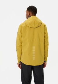 Veste jaune imperméable avec capuche, dotée de points réfléchissants dans le dos pour la visibilité et de poignets élastiques. Texture lisse, design léger.