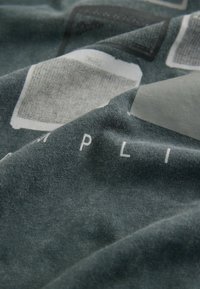 Gray fabric with a soft texture, featuring white printed text and various rectangular graphic elements in darker shades.