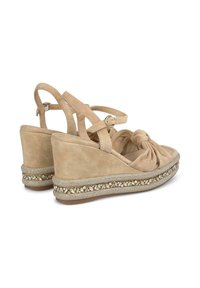 Sandali con zeppa in suede beige, con design annodato, cinturino alla caviglia regolabile e fascia decorata con perle attorno alla base.