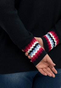 Maglione lavorato a maglia in blu navy scuro con polsini colorati a motivo a zigzag nelle tonalità rosso, blu, bianco e nero; orlo a coste.