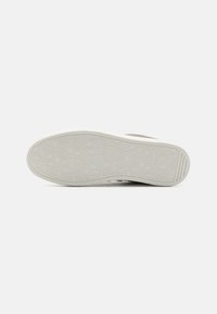 Shoe outsole with hexagonal pattern, white rubber material, curved shape, featuring a textured grip surface. Lightly colored border.