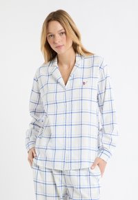 Biała flanelowa piżama z niebieskim wzorem w kratę, długimi rękawami, zapinana na guziki z przodu i małym czerwonym haftem.