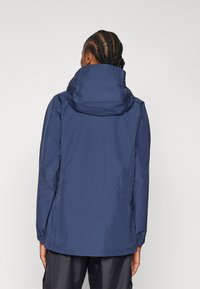 Navy waterproof jacket with a hood, featuring elastic cuffs and a cinched waist. Smooth texture, subtle stitching detail.
