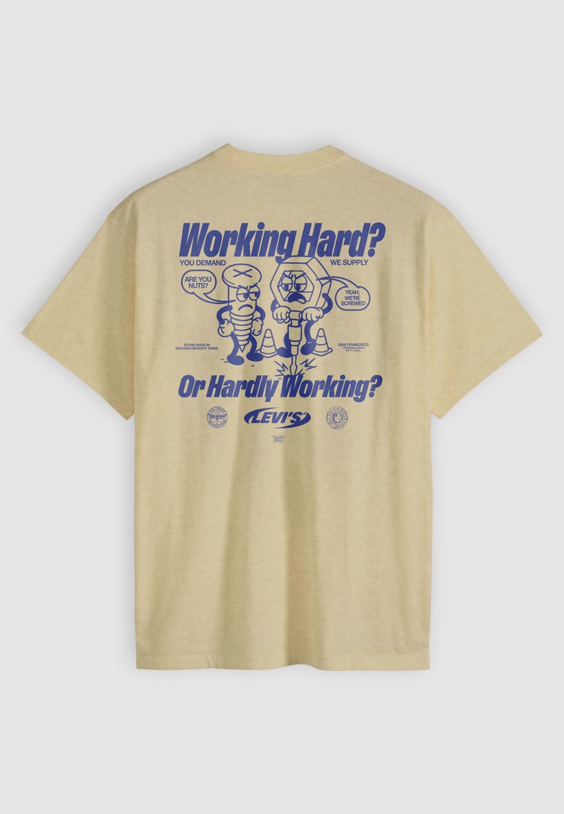 Beiges T-Shirt mit blauer Grafik einer Cartoon-Schraube und Mutter, Text „Working Hard? Or Hardly Working?“ und Levi's-Logo auf der Rückseite.