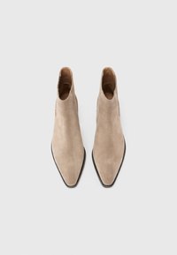 Stivaletti in suede beige alla caviglia con punta affusolata e scollatura bassa, caratterizzati da una texture liscia e una suola nera. Nessun hardware visibile o motivi.