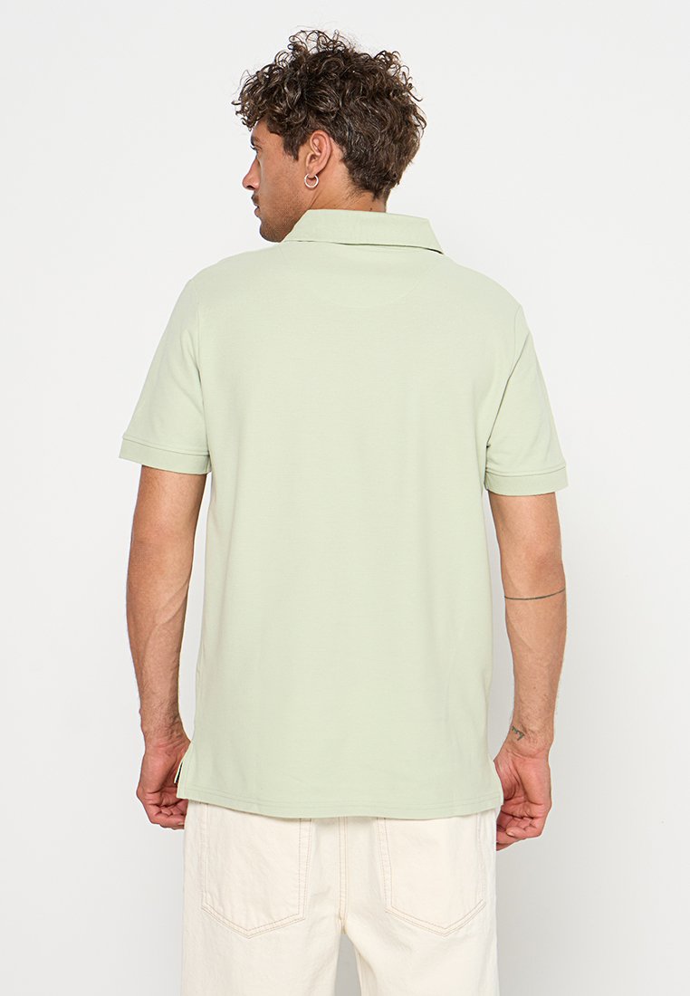 Hellgrünes Poloshirt mit klassischem Kragen, kurzen Ärmeln und geradem Saum. Hergestellt aus einem weichen Stoff mit glatter Textur.