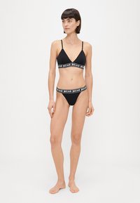 Set di lingerie nera composto da un reggiseno a triangolo e un perizoma abbinato, entrambi con bande elastiche marchiate "justcavalli". Tessuto dalle finiture lisce.