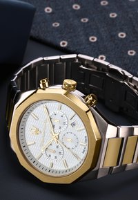 Orologio in metallo dorato e argentato con cassa octagonale, quadrante bianco texturizzato con tre subquadranti, display della data e bracciale a maglie.