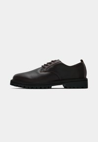 Dark brown leather lace-up dress shoe with thick black rubber sole and rugged tread, shown from the side on a white background.