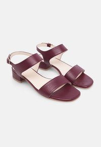 Sandali in pelle color bordeaux scuro con due ampie cinghie sulla parte superiore del piede, design con punta aperta, tacco basso e cinturino alla caviglia regolabile.