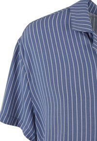 Short-sleeve, collared shirt in light blue fabric with white vertical stripes. Features a relaxed fit and smooth, soft texture.