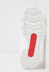 White sneaker with textured rubber sole, featuring a red "Levi's" logo on the heel. Clean design with a smooth finish and minimal detailing.