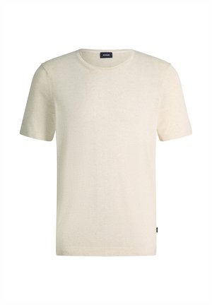 Maglietta a maniche corte in maglia beige tinta unita con collo rotondo, che mostra una piccola etichetta nera del marchio al livello del collo e dell'orlo laterale.