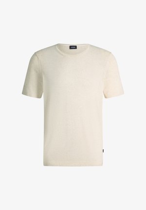 Schlichtes beige Strick-T-Shirt mit kurzen Ärmeln und Rundhalsausschnitt, versehen mit einem kleinen schwarzen Markenlabel am Halsausschnitt und am Seitensaum.