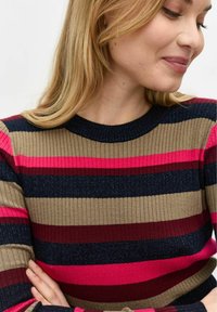 Ribbad tröja med horisontella ränder i rosa, vinröd, marinblå och beige. Urringningen har en klassisk rund stil. Mjuk textur.