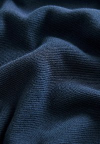 Dunkelblaues, strukturiertes Gewebe mit einem feinen Strickmuster und subtilen Schattierungsvariationen, die ein weiches, texturiertes Aussehen erzeugen.