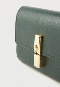 Portofel verde din piele texturată, cu o închizătoare aurie, având un finisaj neted și linii clare, evidențiind un design minimalist.