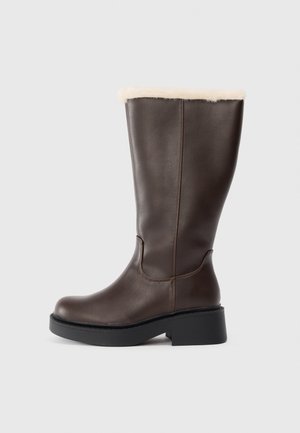 Brown leather knee-high boots with a soft beige fur lining at the top, featuring a chunky black platform sole and a sleek shape.
