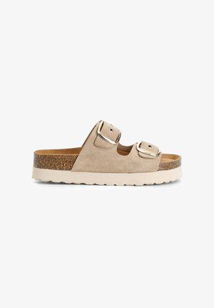 Sandalia deslizante de ante beige con dos correas ajustables, hebillas metálicas y una plantilla de corcho texturizada. Suela exterior de goma ligera.