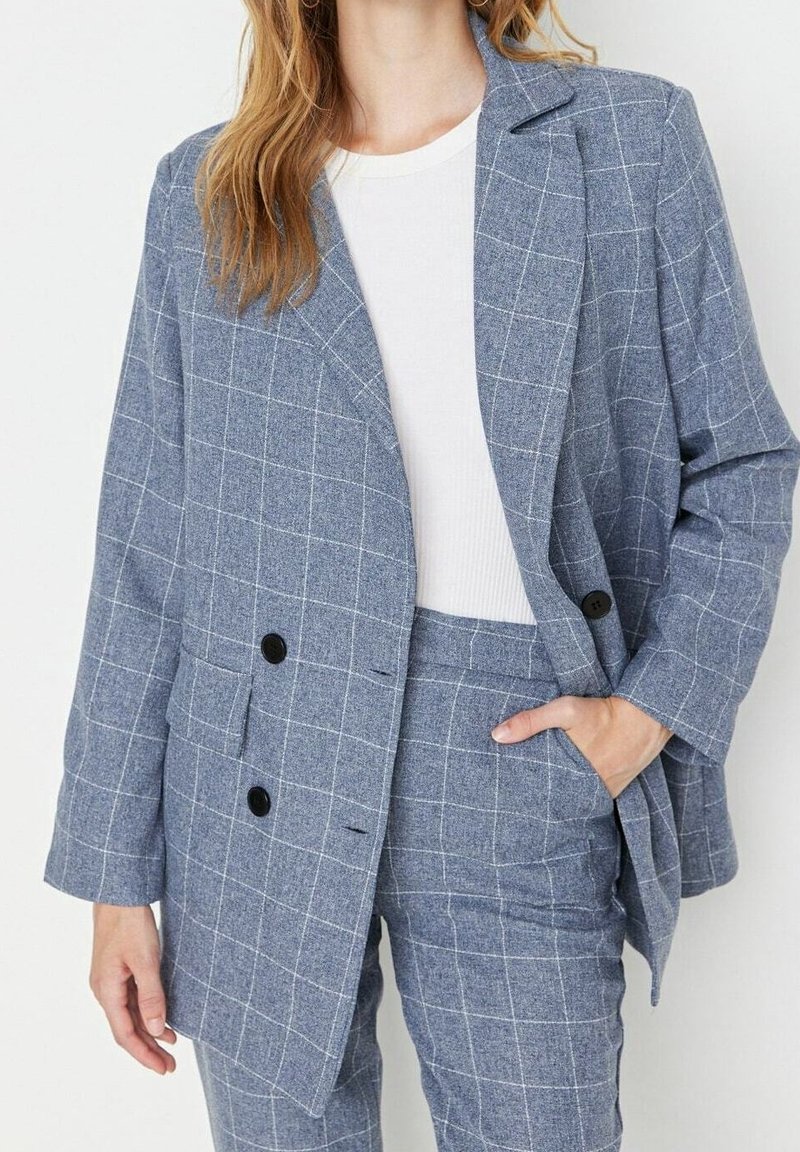 Blazer à carreaux bleu clair avec une coupe décontractée, revers crantés, deux boutons noirs et poches plaquées, fabriqué en tissu texturé.
