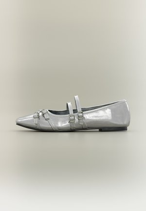 Chaussure plate argentée brillante pointue avec deux fines brides à boucle sur le dessus et des boucles décoratives près des orteils.