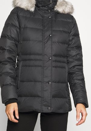Sort puffjakke med høj krave, der har en aftagelig faux fur-besætning, quiltet design og sorte trykknapper foran.