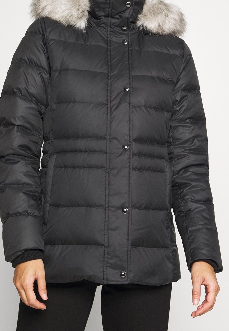 Chaqueta de plumas negra con un cuello alto, con un ribete de pelo sintético desmontable, diseño acolchado y botones a presión negros en el frente.
