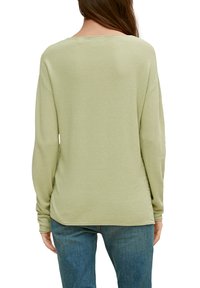 Długi rękaw, jasnozielony sweter z teksturowanej tkaniny, luźny krój i okrągły dół. Widok z tyłu pokazuje prosty, minimalistyczny design.