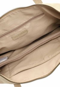 Interior de bolso tote de lona beige con bolsillo con cremallera, dos bolsillos abiertos, tela texturizada y etiqueta en relieve con las palabras "EMILY & NOAH".