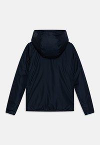 Giacca leggera blu navy con cappuccio, caratterizzata da un esterno liscio e lucido e polsini elasticizzati sulle maniche, senza branding visibile.