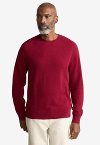Roter gestrickter Pullover mit Rundhalsausschnitt, langen Ärmeln und strukturiertem Stoff. Verfügt über gerippte Bündchen und Saum, hat ein weiches und warmes Aussehen.