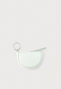 Μικρό πορτοφολάκι σε παστέλ πράσινο χρώμα σε σχήμα ημισελήνου με φερμουάρ και ασημένιο μπρελόκ Calvin Klein, πάνω σε απλό λευκό φόντο.