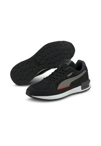 Zapatillas deportivas negras con parte superior de malla ligera, suela de goma con agarre texturizado y acentos en gris y rojo contrastantes.