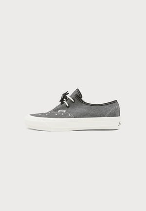 Γκρι χαμηλό παπούτσι Vans με λευκή σόλα, λευκή ραφή, ασπρόμαυρα κορδόνια και μικρή ετικέτα λογότυπου στο πλάι.