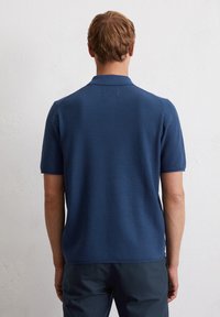 Marineblauw polo shirt met korte mouwen, gemaakt van een textuurgebreide stof en voorzien van een kraag. Het shirt heeft een rechte onderkant en ribgebreide manchetten. Achteraanzicht weergegeven.